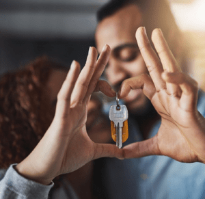 A couple making a heart with their hands with the keys in the middle