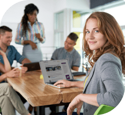 A smiling woman at a table using her small business banking tools online