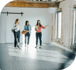 A real estate agent shows an empty house to two women