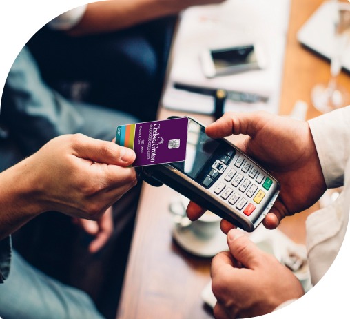 A man taps a purple Chelsea Groton visa debit card to a payment machine