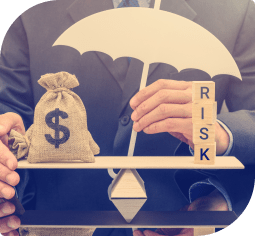 A hand balances a scale with a bag of money on the left, stacked scrabble pieces reading "RISK" on the right, and a white umbrella in the middle