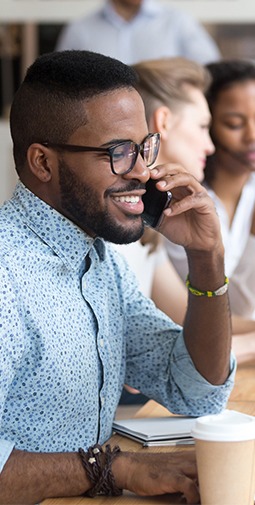 A man with glasses smiling with on the phone