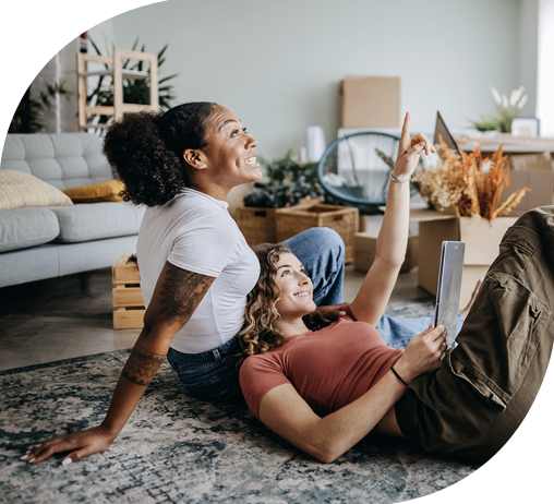 Happy female couple sitting closely together talking about their financial dreams