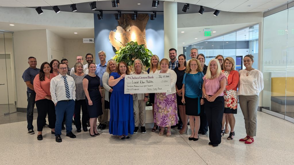 Team members pose at Headquarters with Acts of Kindness check